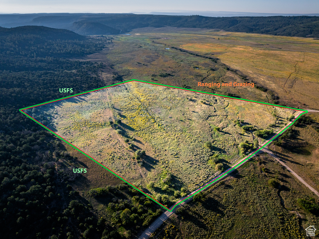 Aerial view of sparsely populated area featuring property parcel outlined and a mountainous background