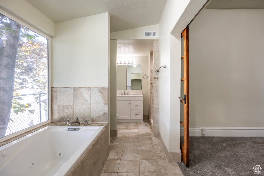 Full bath with vanity, a tub with jets, and lofted ceiling