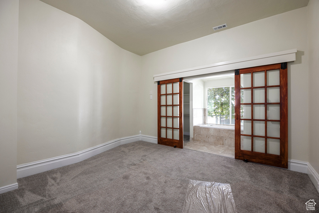 Carpeted empty room featuring vaulted ceiling and baseboards