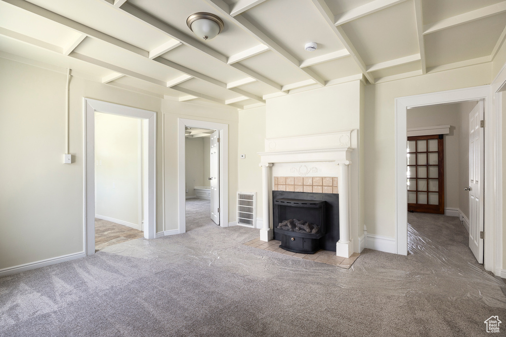 Unfurnished living room with carpet floors, a tiled fireplace, and baseboards