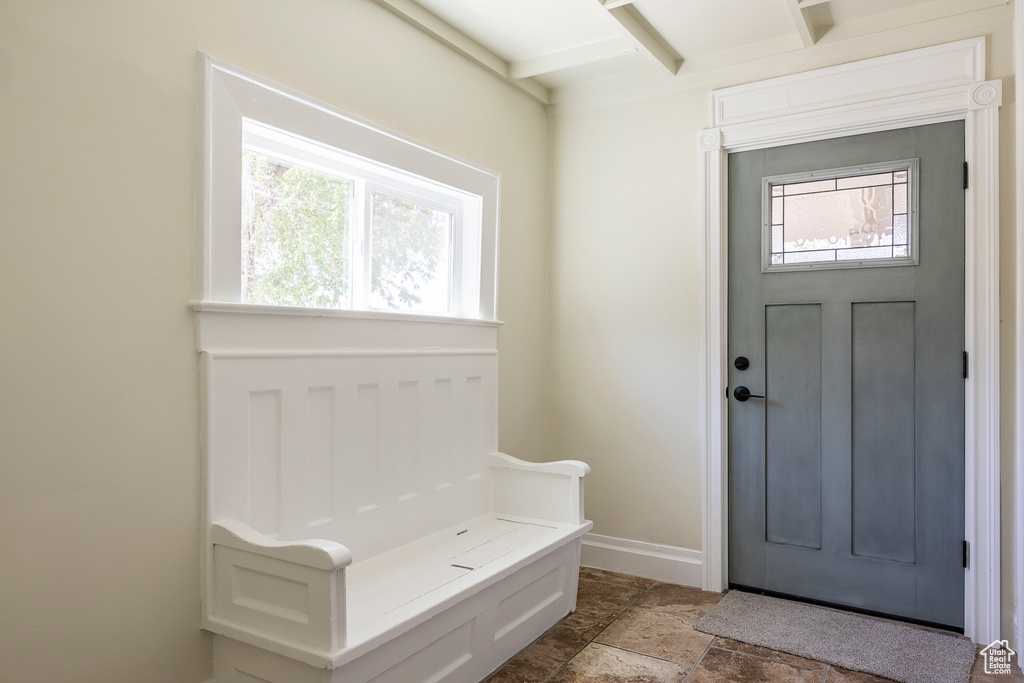 Foyer entrance with stone finish flooring, baseboards, and beam ceiling