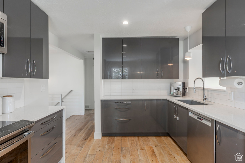 Kitchen featuring appliances with stainless steel finishes, a sink, modern cabinets, decorative backsplash, and recessed lighting