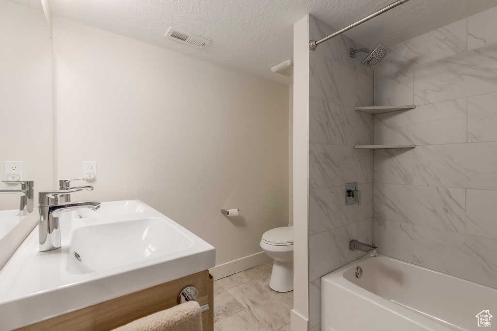 Bathroom with vanity, bathing tub / shower combination, toilet, baseboards, and a textured ceiling