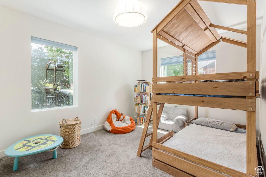Carpeted bedroom with multiple windows and baseboards