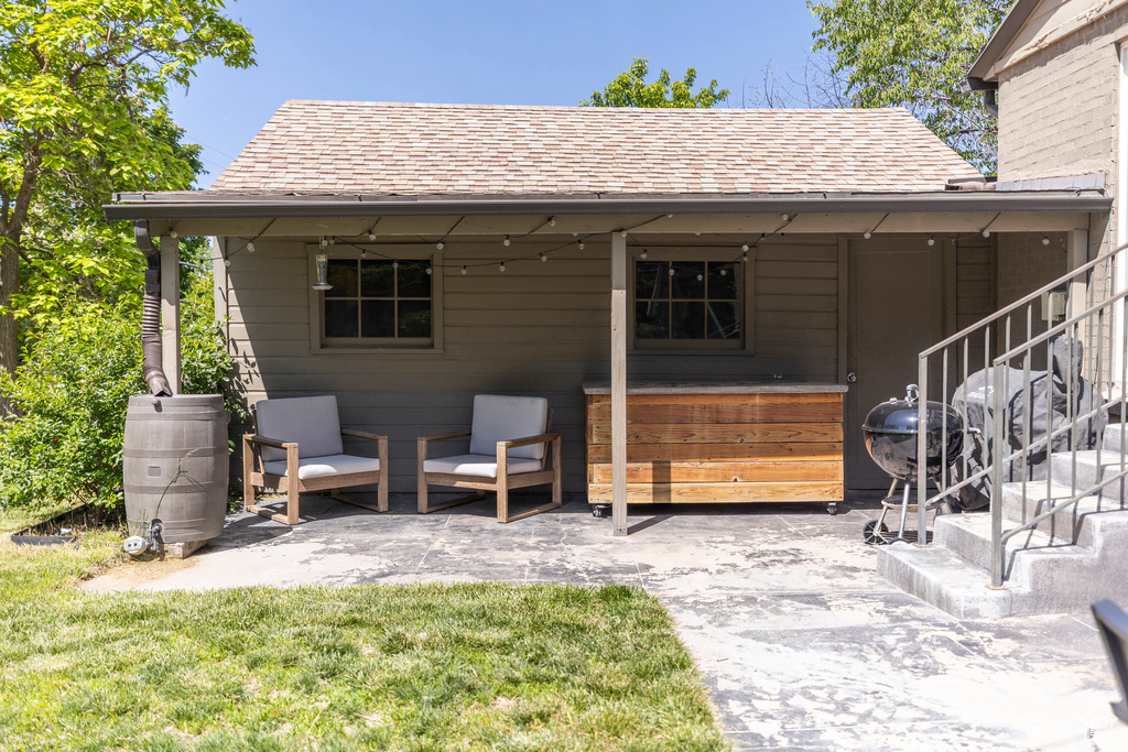 Back of house with roof with shingles, a patio area, stairway, and a yard