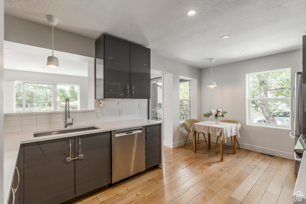 Kitchen featuring dishwasher, a sink, light countertops, plenty of natural light, and recessed lighting
