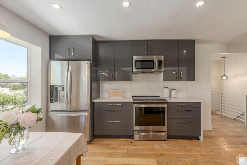 Kitchen with stainless steel appliances, gray cabinetry, light wood-type flooring, and recessed lighting