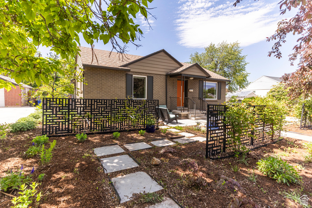 View of front of house featuring brick siding and roof with shingles