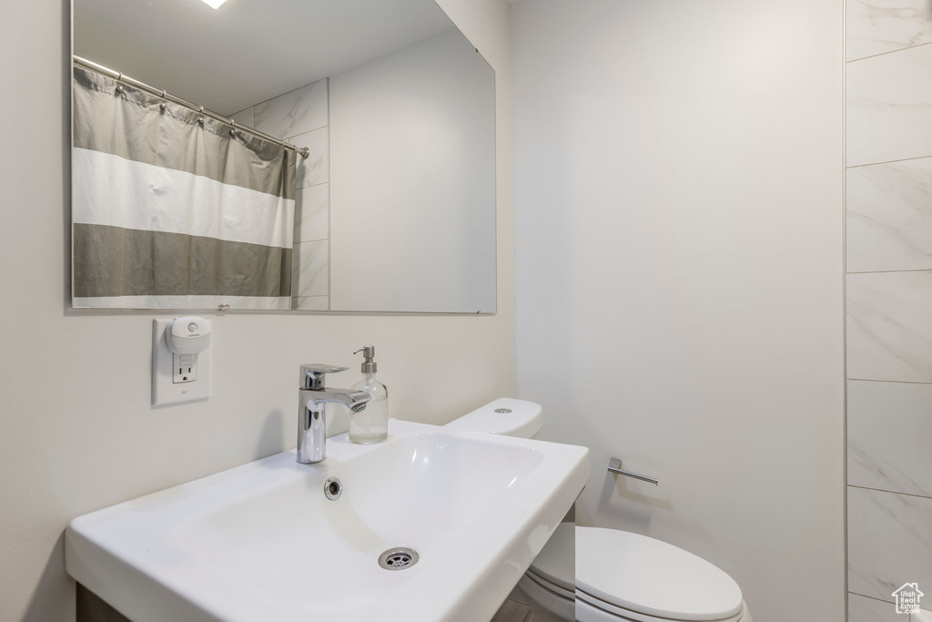 Full bath with toilet, a sink, and curtained shower