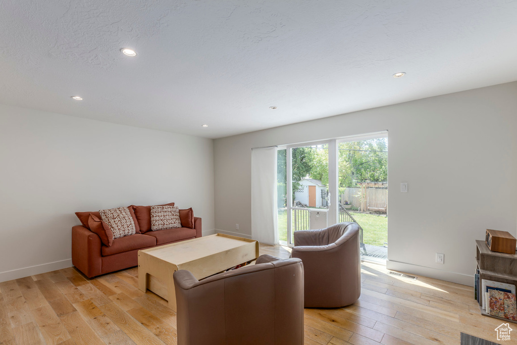 Living room with light wood-type flooring, baseboards, and recessed lighting