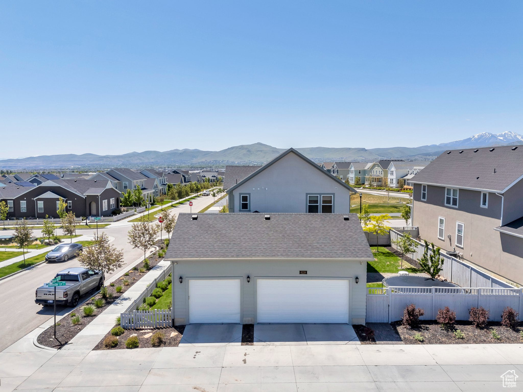 View of front facade featuring a residential view, a mountain view, driveway, and a shingled roof