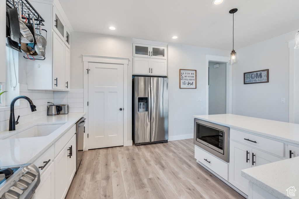 Kitchen with stainless steel appliances, a sink, light wood-type flooring, recessed lighting, and white cabinets