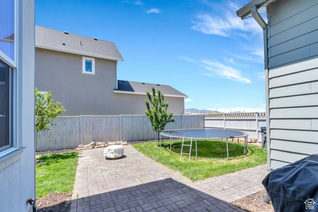 Fenced backyard with a patio area and a trampoline