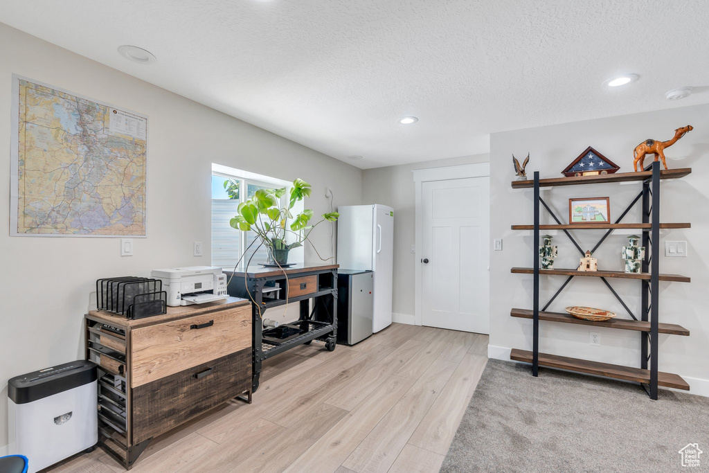 Home office with recessed lighting, light wood-style flooring, a textured ceiling, and baseboards