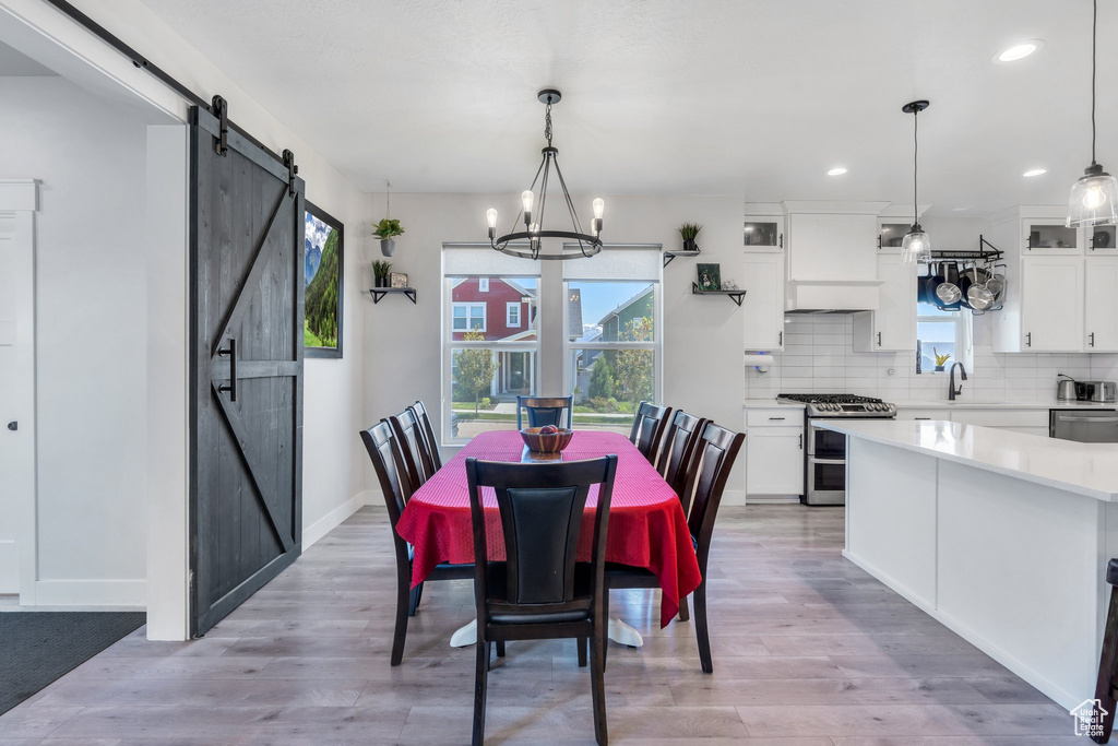 Dining area featuring a barn door, a chandelier, light wood-style flooring, recessed lighting, and baseboards