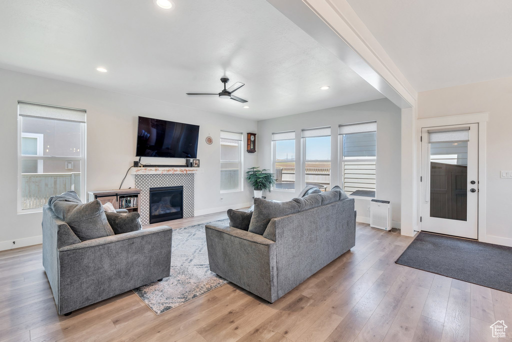 Living room featuring ceiling fan, a tile fireplace, light wood-type flooring, baseboards, and recessed lighting