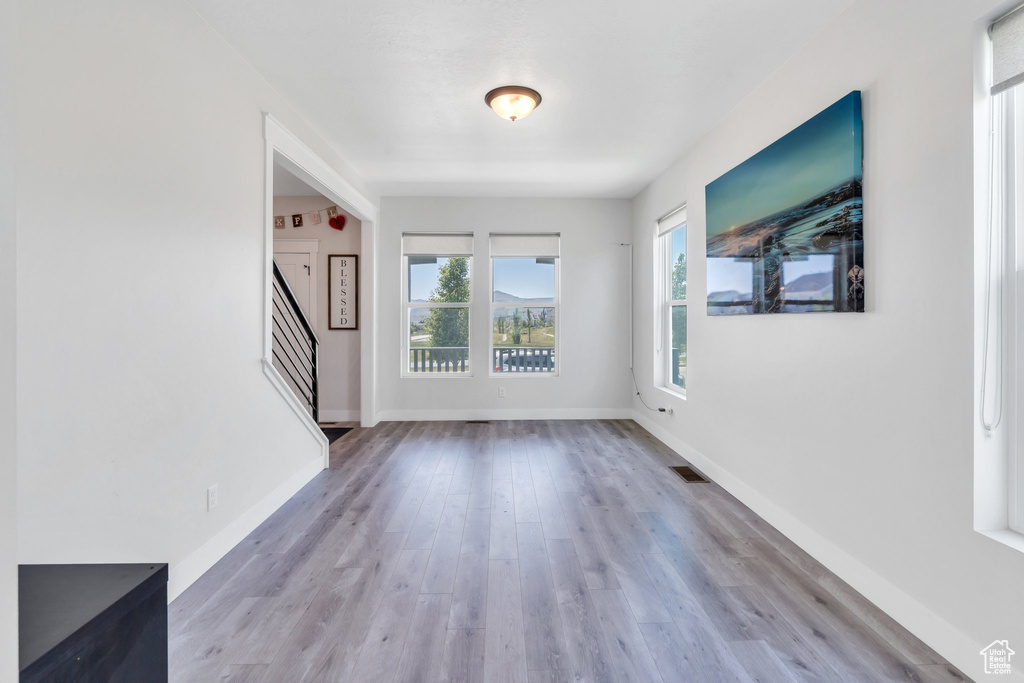 Unfurnished living room with stairway, wood finished floors, and baseboards