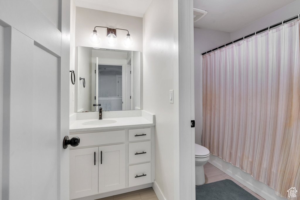 Bathroom featuring toilet, vanity, tile patterned flooring, and shower / bathtub combination with curtain