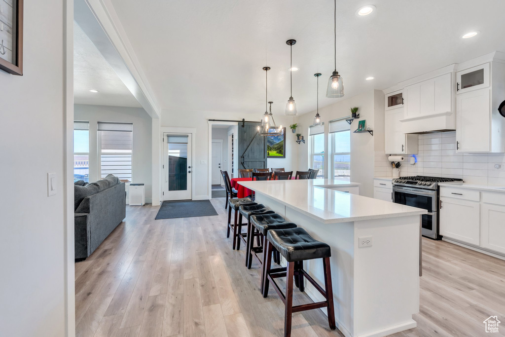 Kitchen featuring double oven range, a barn door, light wood-style flooring, a center island, and backsplash