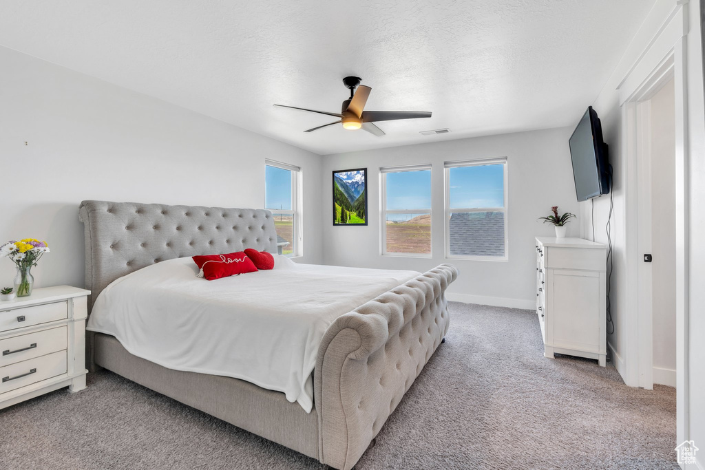 Bedroom featuring light carpet, baseboards, and a ceiling fan