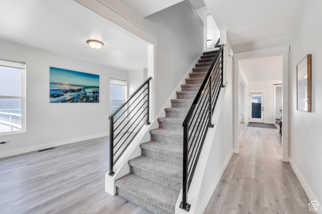Staircase featuring wood finished floors, healthy amount of natural light, and baseboards