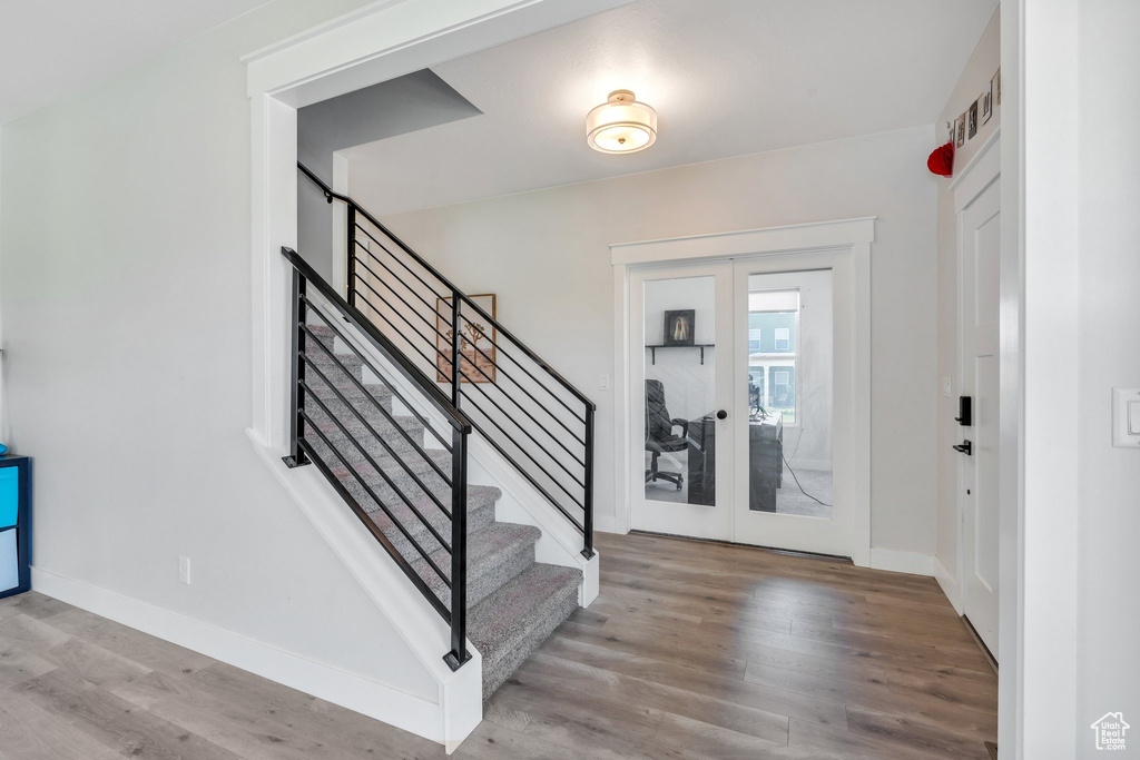 Foyer entrance with french doors, wood finished floors, stairway, and baseboards