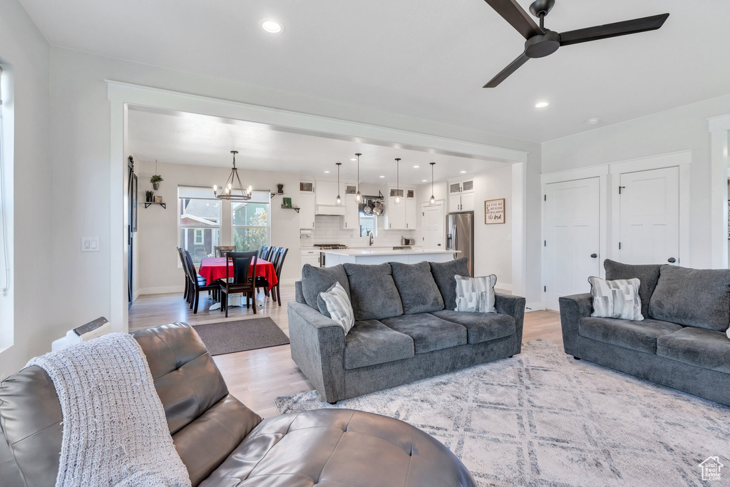 Living room with a ceiling fan, light wood finished floors, a chandelier, recessed lighting, and baseboards