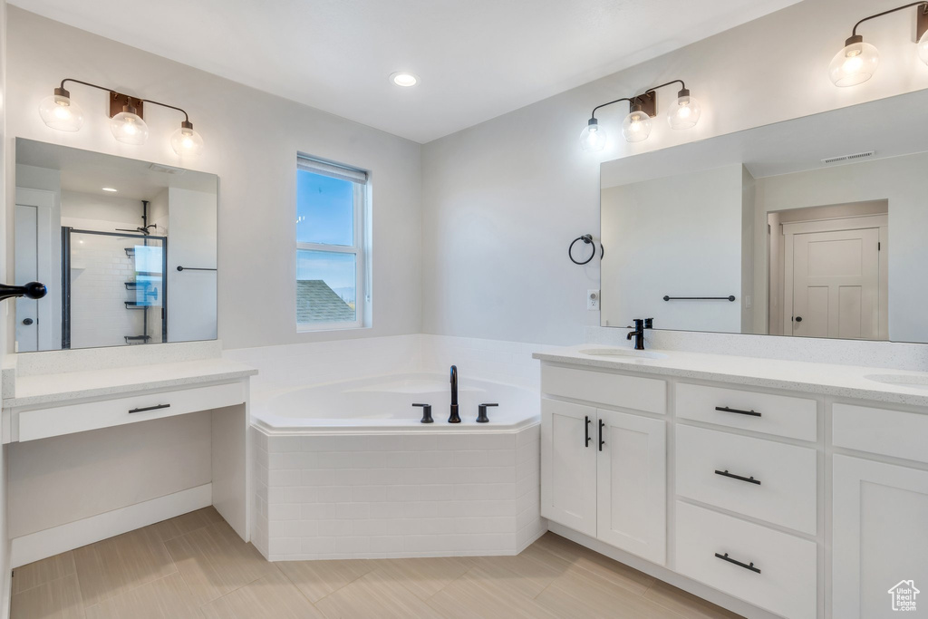 Bathroom with double vanity, a garden tub, and a stall shower
