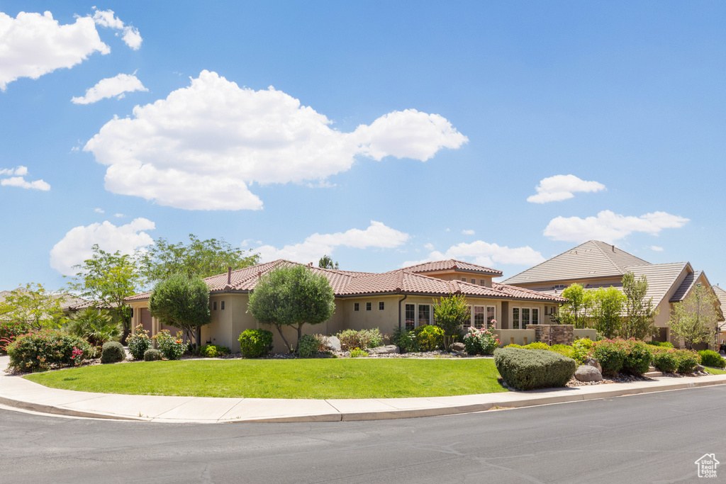 Mediterranean / spanish home with a tiled roof, stucco siding, and a front yard