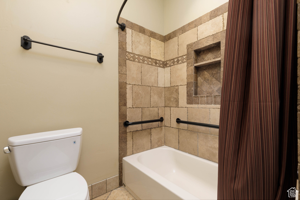 Bathroom with toilet and shower / bathtub combination with curtain