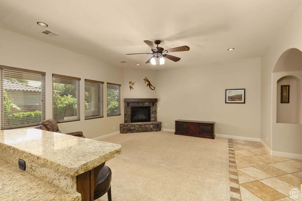 Living room with a stone fireplace, recessed lighting, baseboards, light tile patterned floors, and arched walkways