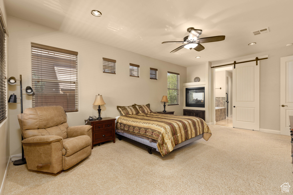 Bedroom featuring a barn door, carpet, recessed lighting, ensuite bath, and ceiling fan