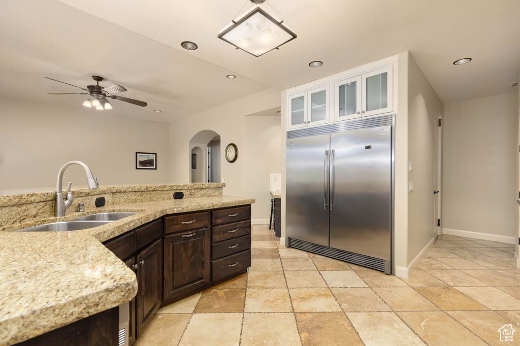 Kitchen with stainless steel built in fridge, arched walkways, a sink, a ceiling fan, and dark brown cabinets