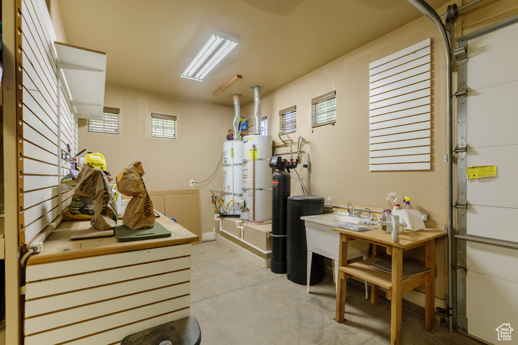 Garage with strapped water heater, a sink, and water heater