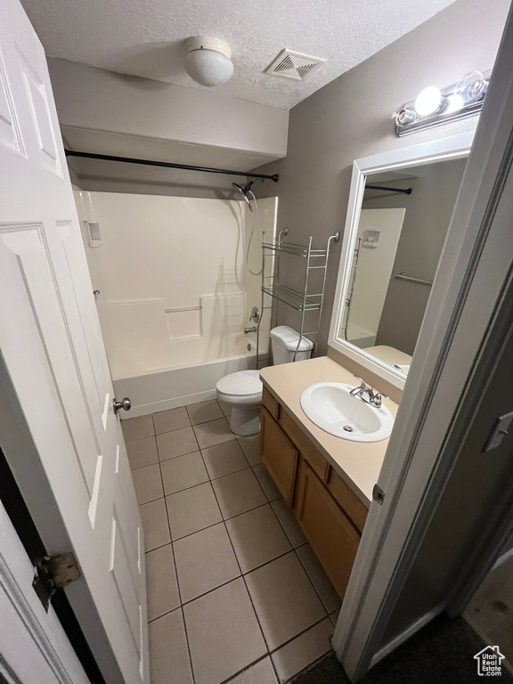 Bathroom with tile patterned flooring, toilet, vanity, bathing tub / shower combination, and a textured ceiling