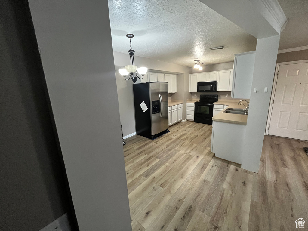 Kitchen featuring black appliances, a sink, light wood-type flooring, light countertops, and white cabinets
