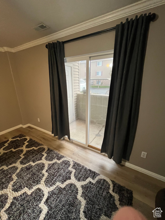 Unfurnished room featuring crown molding, wood finished floors, and baseboards