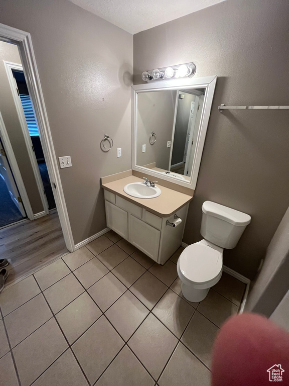 Half bath featuring toilet, tile patterned flooring, vanity, and baseboards