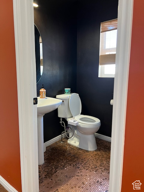 Half bath with baseboards and toilet