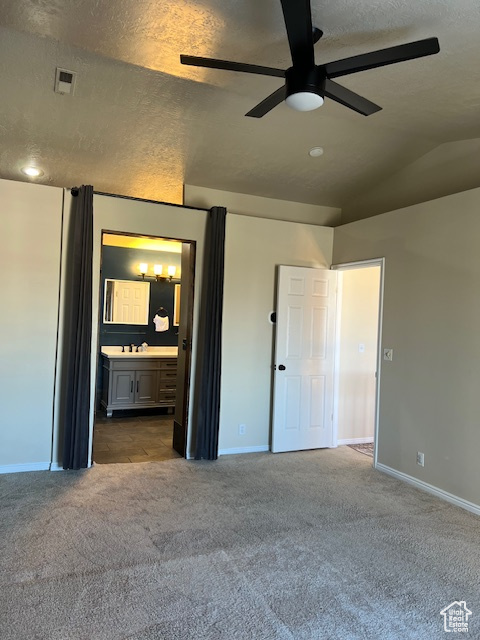 Unfurnished bedroom featuring carpet floors, a textured ceiling, baseboards, ensuite bath, and a ceiling fan