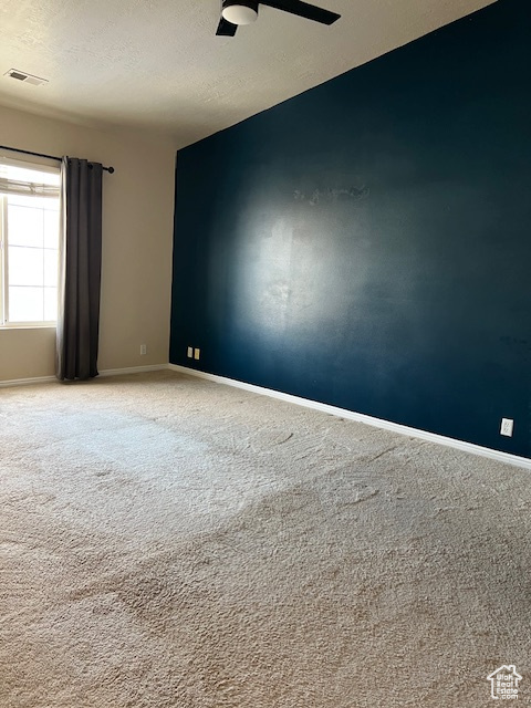 Unfurnished room with a textured ceiling, carpet flooring, a ceiling fan, and baseboards