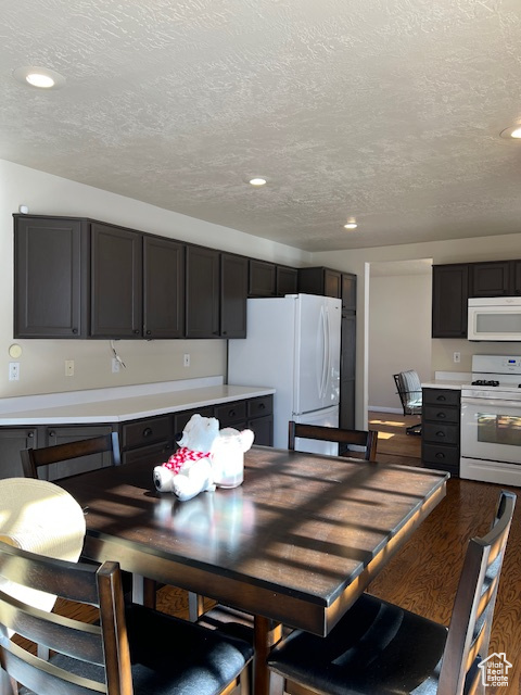 Kitchen with white appliances, light countertops, a textured ceiling, recessed lighting, and wood finished floors