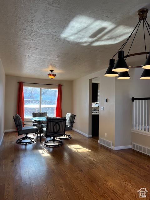 Dining room featuring wood finished floors, a textured ceiling, and baseboards