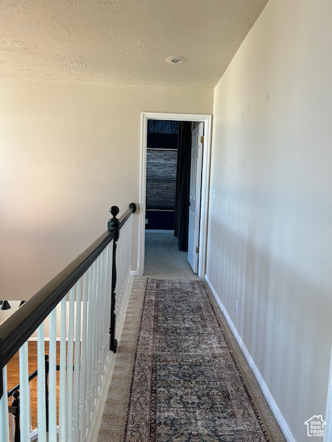 Corridor with carpet and a textured ceiling