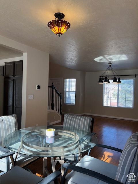 Dining area featuring stairs, baseboards, wood finished floors, a textured ceiling, and a chandelier