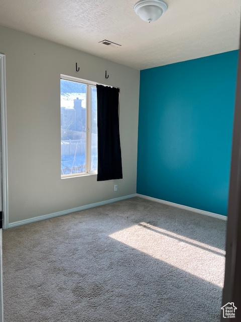Carpeted spare room with baseboards and a textured ceiling