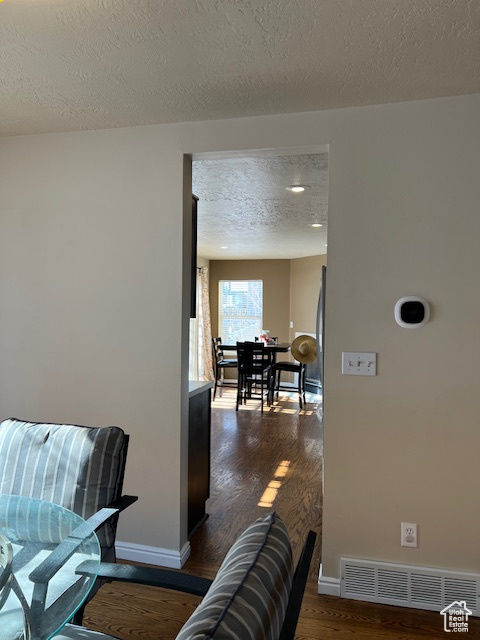 Hall featuring dark wood-type flooring, a textured ceiling, and baseboards