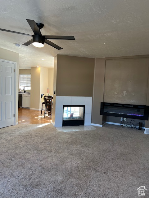 Unfurnished living room with a fireplace, carpet, a ceiling fan, a textured ceiling, and baseboards