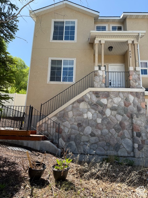 View of front facade featuring stucco siding, stairs, and stone siding