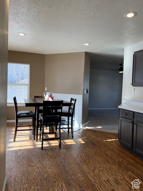 Dining space with a textured ceiling, recessed lighting, dark wood-style flooring, and baseboards